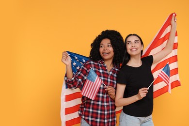 Photo of 4th of July - Independence Day of USA. Happy women with American flags on yellow background. Space for text