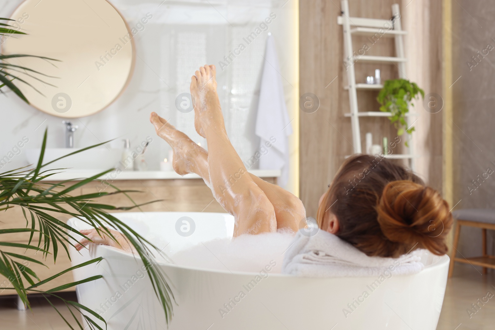 Photo of Woman enjoying bubble bath at home, back view