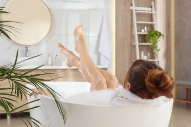 Woman enjoying bubble bath at home, back view