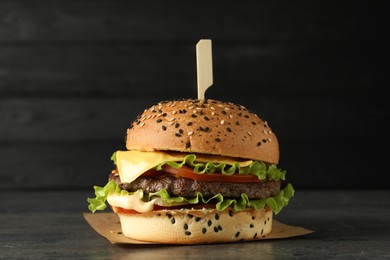 Photo of Burger with delicious patty on gray table against dark background