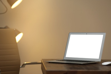 Photo of Laptop with blank screen on table indoors. Space for text