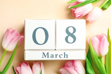 Photo of Wooden block calendar with date 8th of March and tulips on beige background, flat lay. International Women's Day