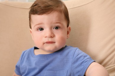 Photo of Cute baby boy sitting in armchair at home