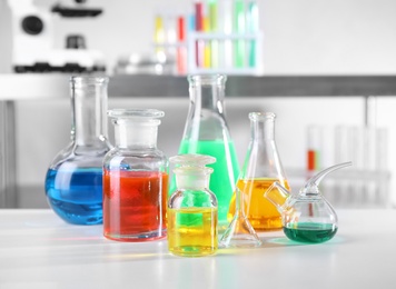 Photo of Different glassware with samples on table in chemistry laboratory