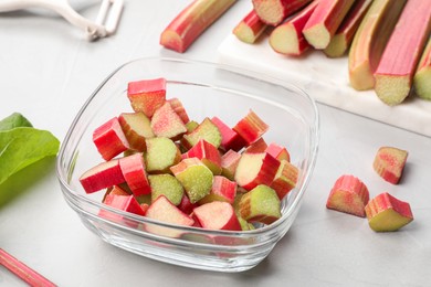 Whole and cut rhubarb stalks on white table, closeup