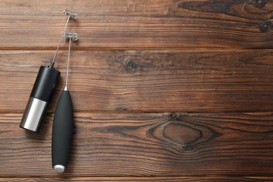 Photo of Black milk frother wands on wooden table, top view. Space for text