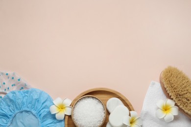 Flat lay composition with shower caps and toiletries on beige background. Space for text