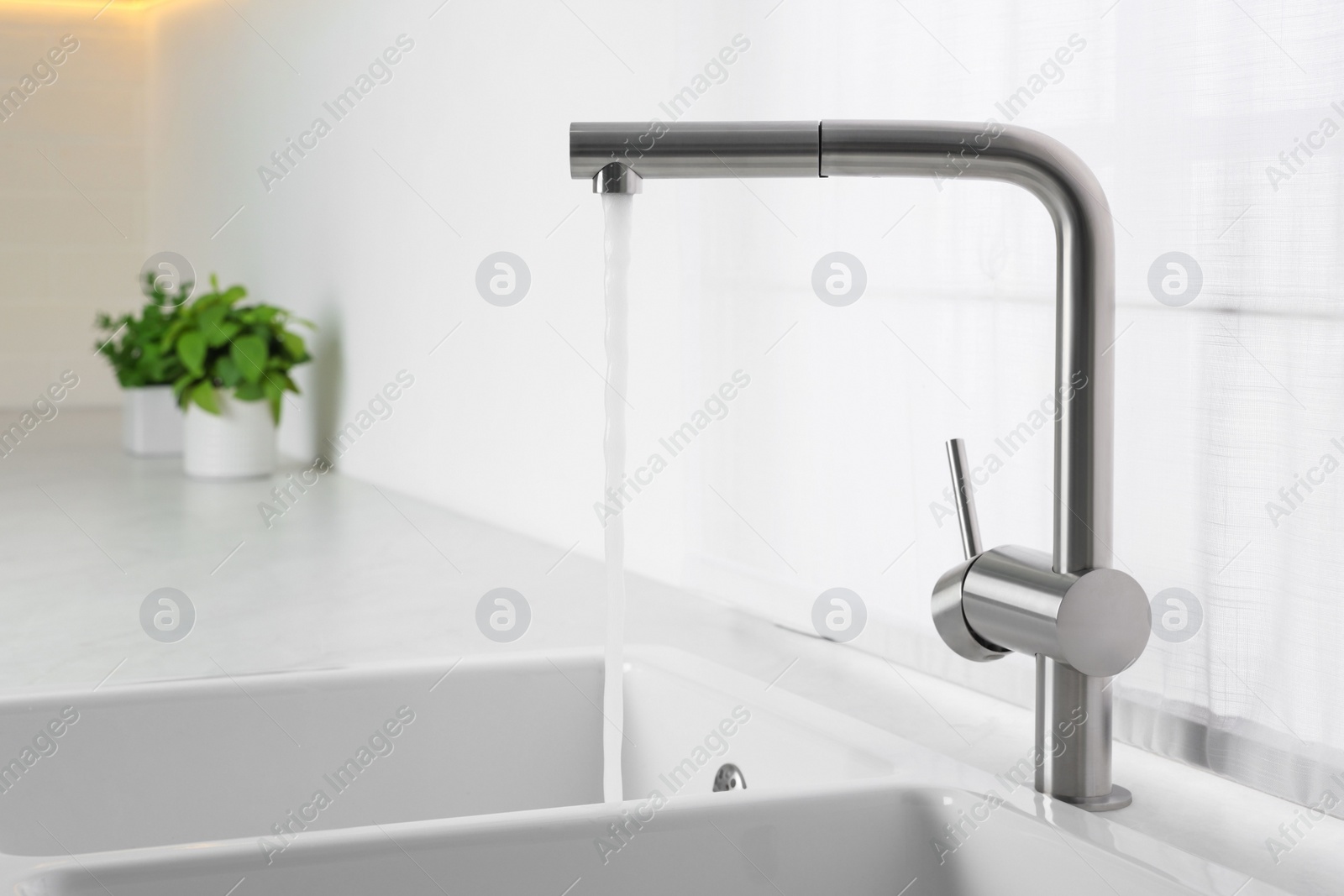 Photo of Stream of water flowing from tap in kitchen