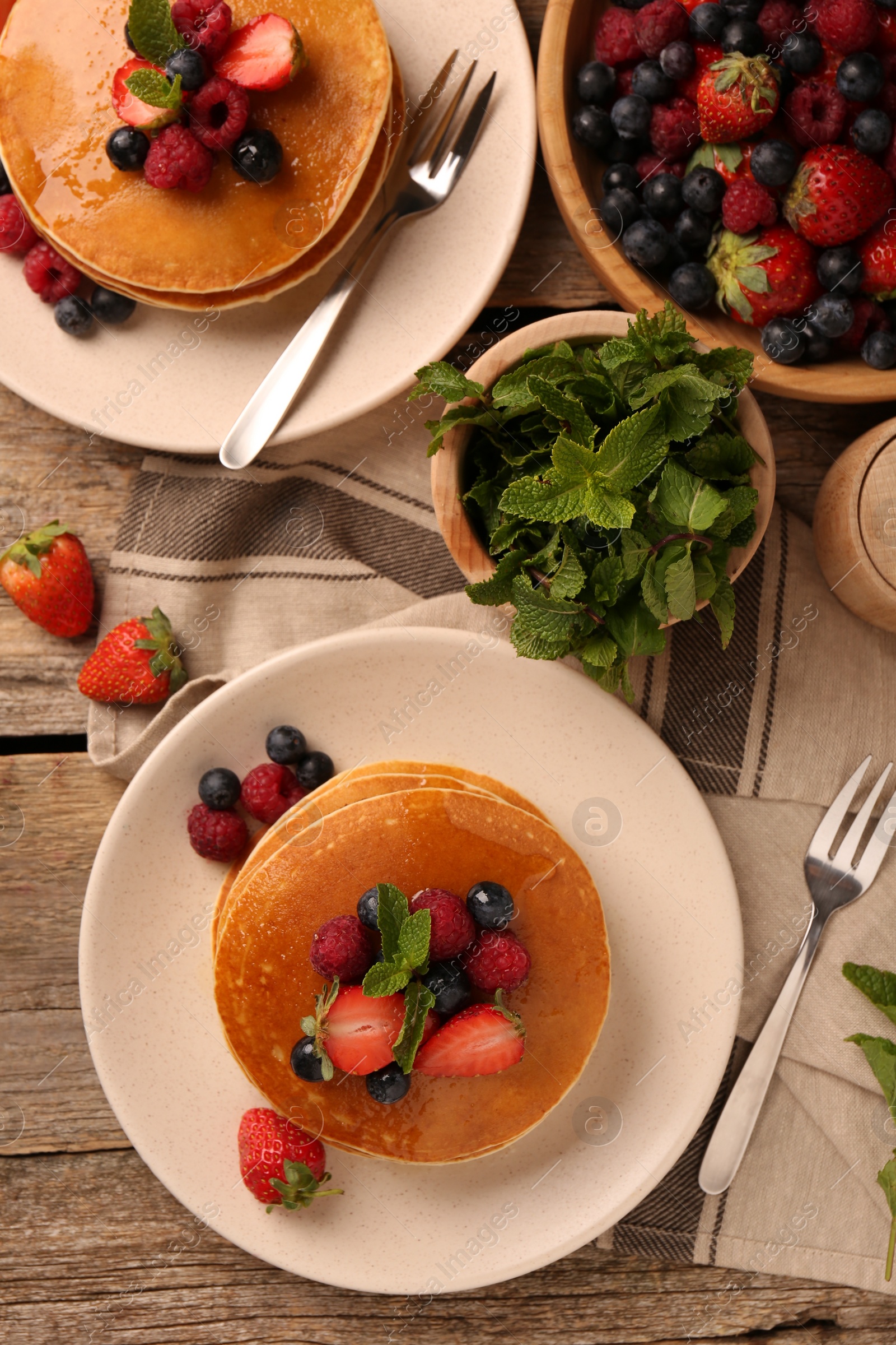 Photo of Tasty pancakes with fresh berries and mint on wooden table, flat lay