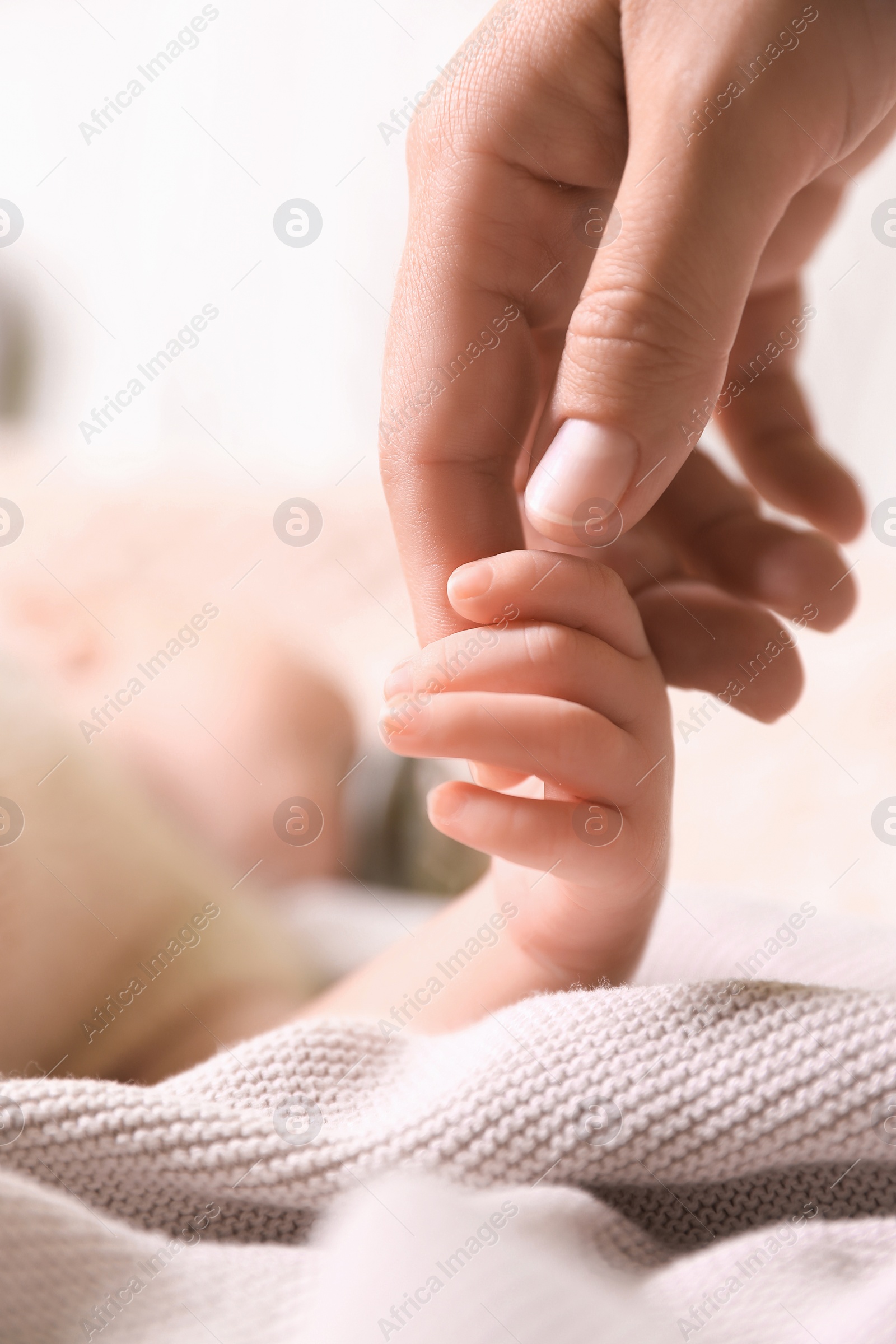 Photo of Mother and her newborn baby on light grey knitted plaid, closeup