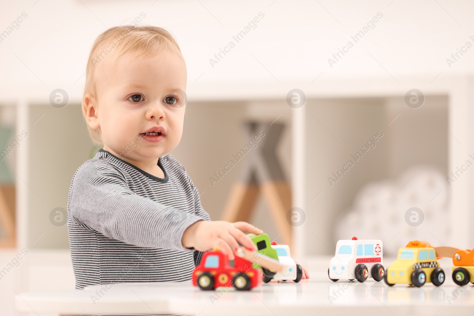 Photo of Children toys. Cute little boy playing with toy cars at white table in room, space for text