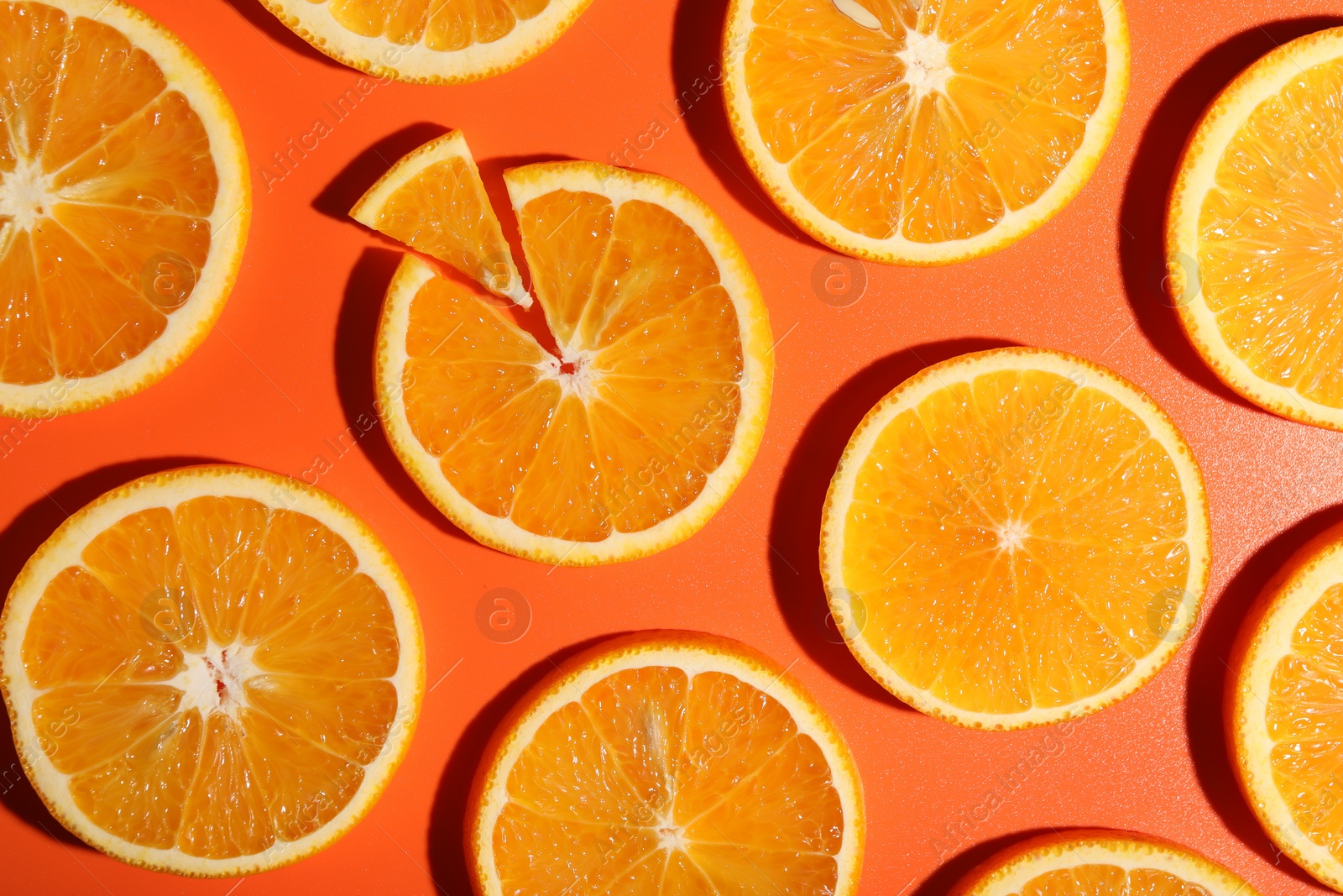 Photo of Slices of juicy orange on terracotta background, flat lay