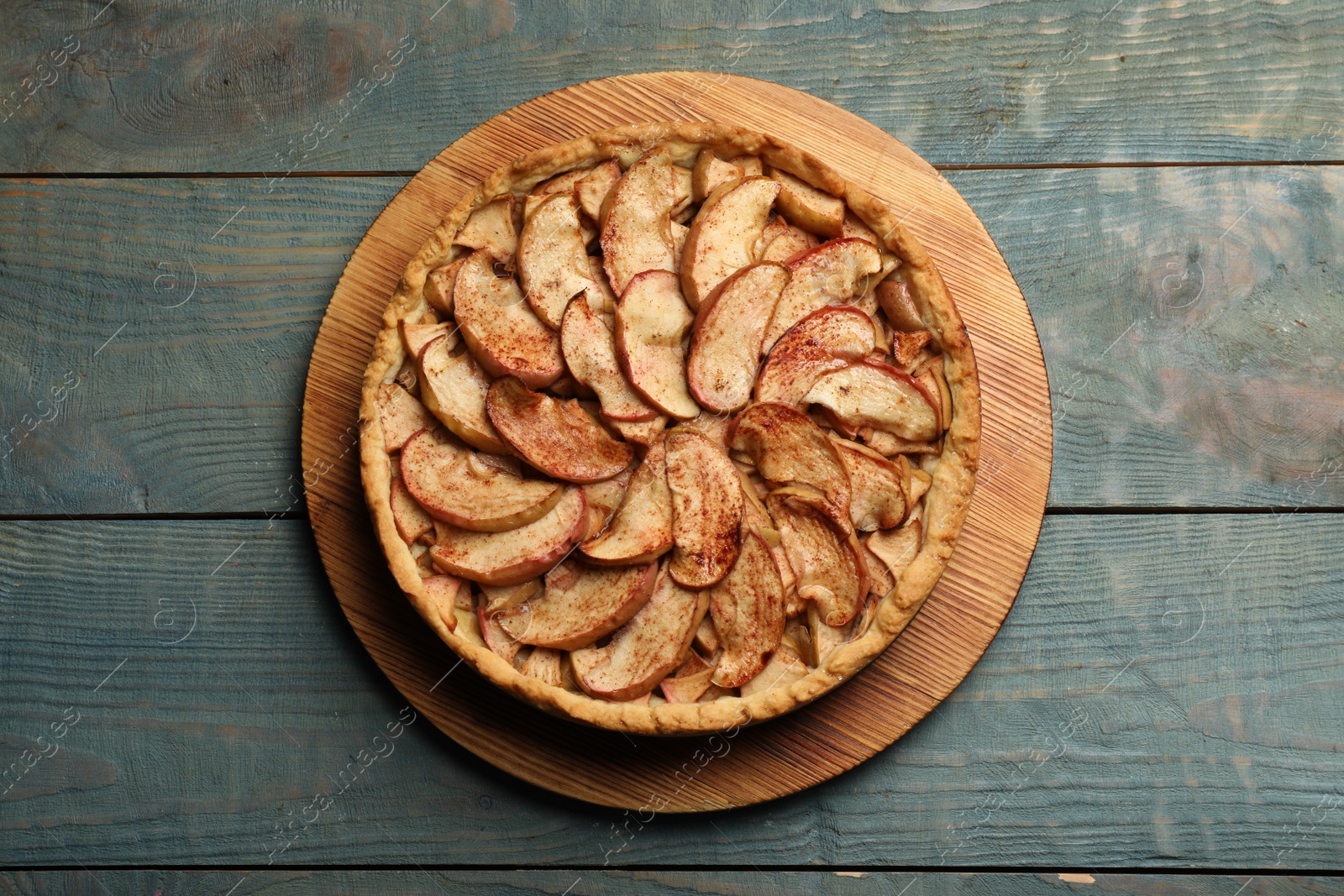 Photo of Delicious apple pie on light blue wooden table, top view