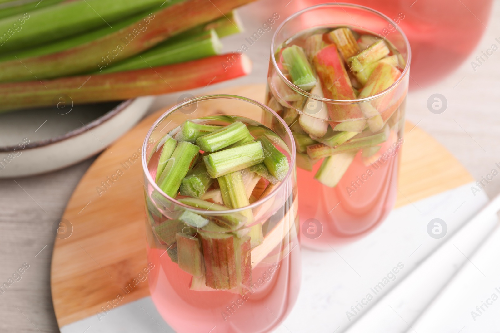 Photo of Glasses of tasty rhubarb cocktail on wooden table, closeup