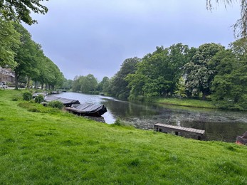 Picturesque view of green park with boats near river outdoors