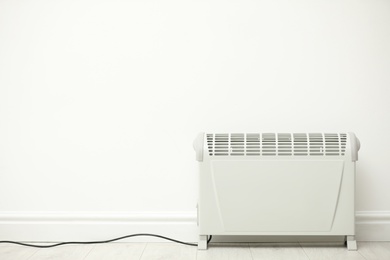 Photo of Modern electric heater near white wall indoors. Space for text