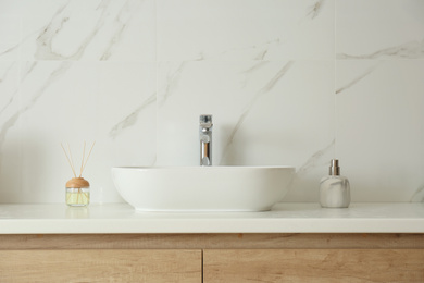 Photo of Bathroom counter with sink, soap dispenser and reed air freshener