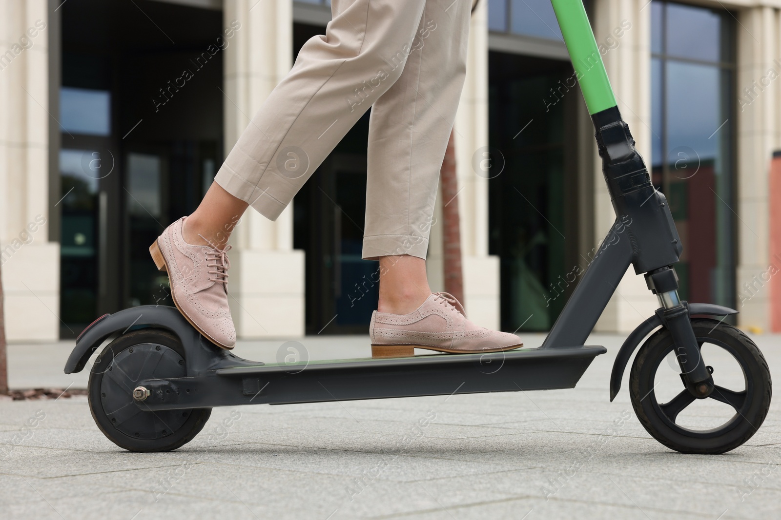 Photo of Businesswoman riding electric kick scooter on city street, closeup