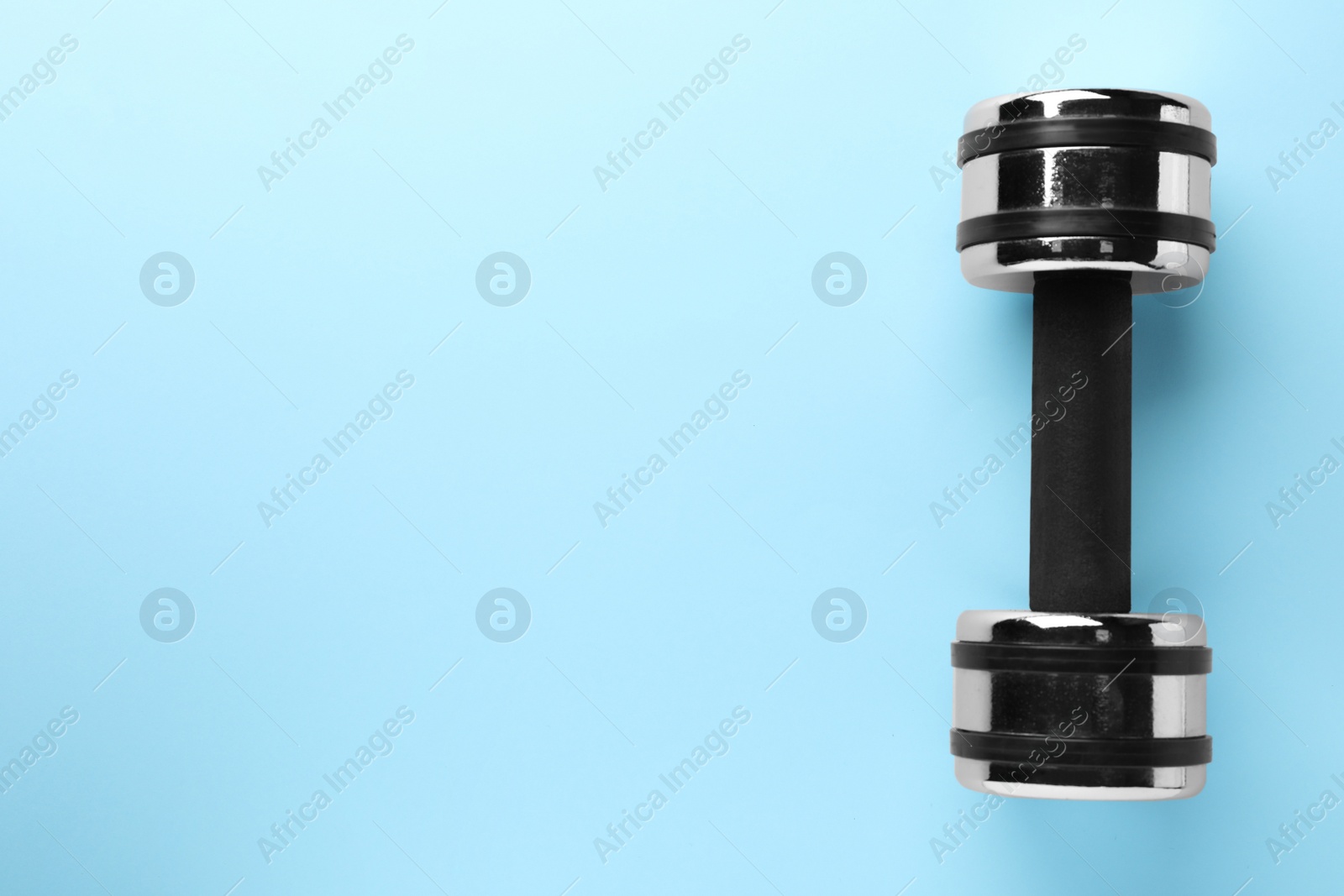 Photo of Stylish dumbbell on light blue background, top view. Space for text
