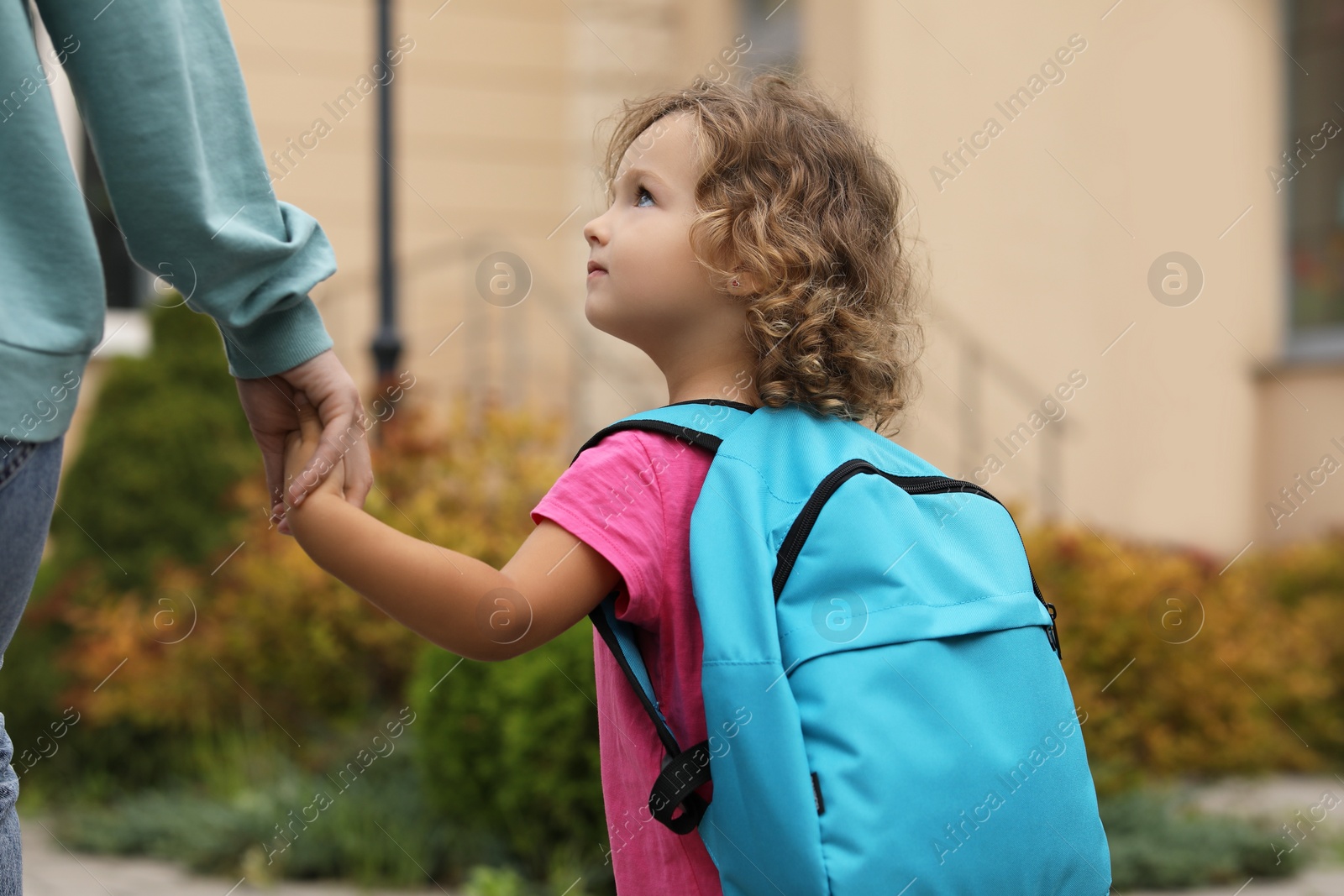 Photo of Woman and her little daughter on their way to kindergarten outdoors