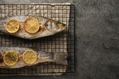 Photo of Baked fish with lemon on grey textured table, top view. Space for text