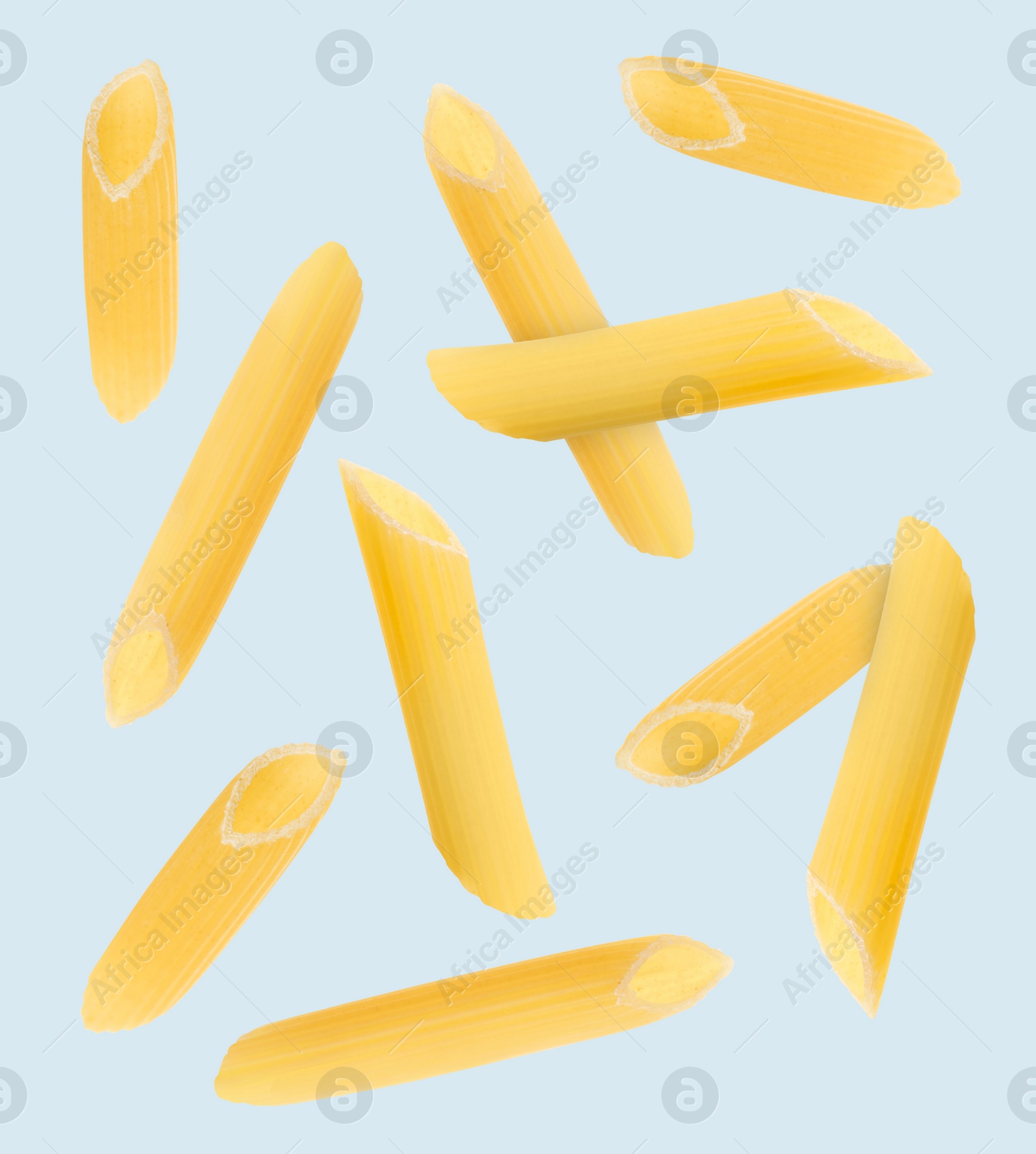 Image of Raw penne pasta flying on light blue background