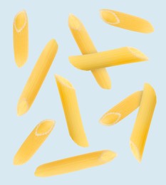 Raw penne pasta flying on light blue background