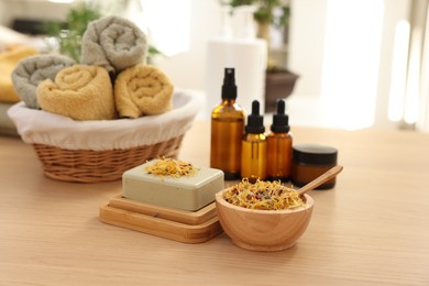 Photo of Soap bar, dry flowers, bottles of essential oils, jar with cream and towels on wooden table indoors. Spa time