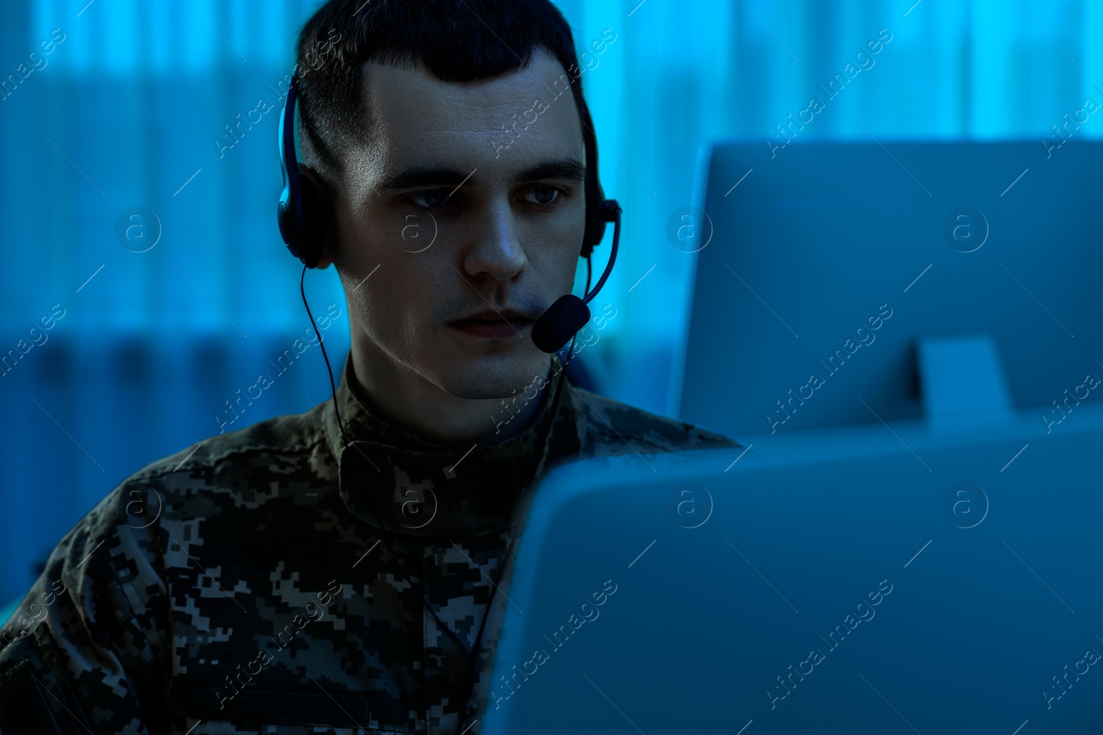 Image of Military service. Soldier in headphones working in office at night