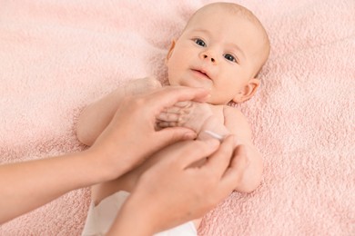 Woman applying body cream onto baby`s skin on bed, top view