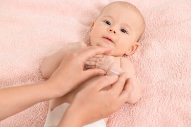 Photo of Woman applying body cream onto baby`s skin on bed, top view