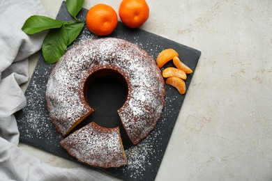 Delicious homemade yogurt cake with tangerines and powdered sugar on gray table, flat lay