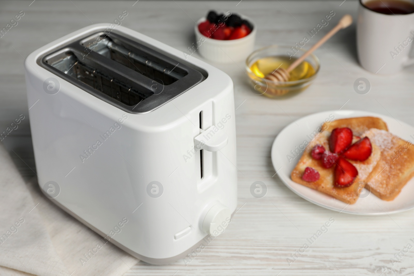 Photo of Modern toaster and bread with fresh berries on white wooden table