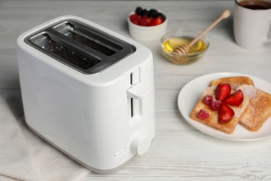 Photo of Modern toaster and bread with fresh berries on white wooden table