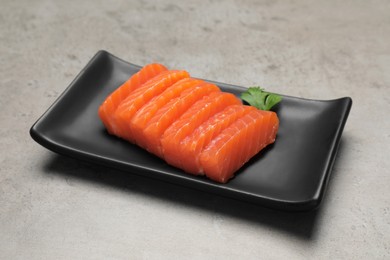 Photo of Plate of tasty salmon slices and parsley on grey table. Delicious sashimi dish