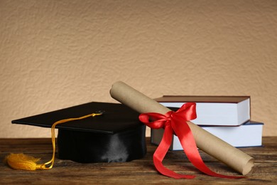 Graduation hat, books and diploma on wooden table