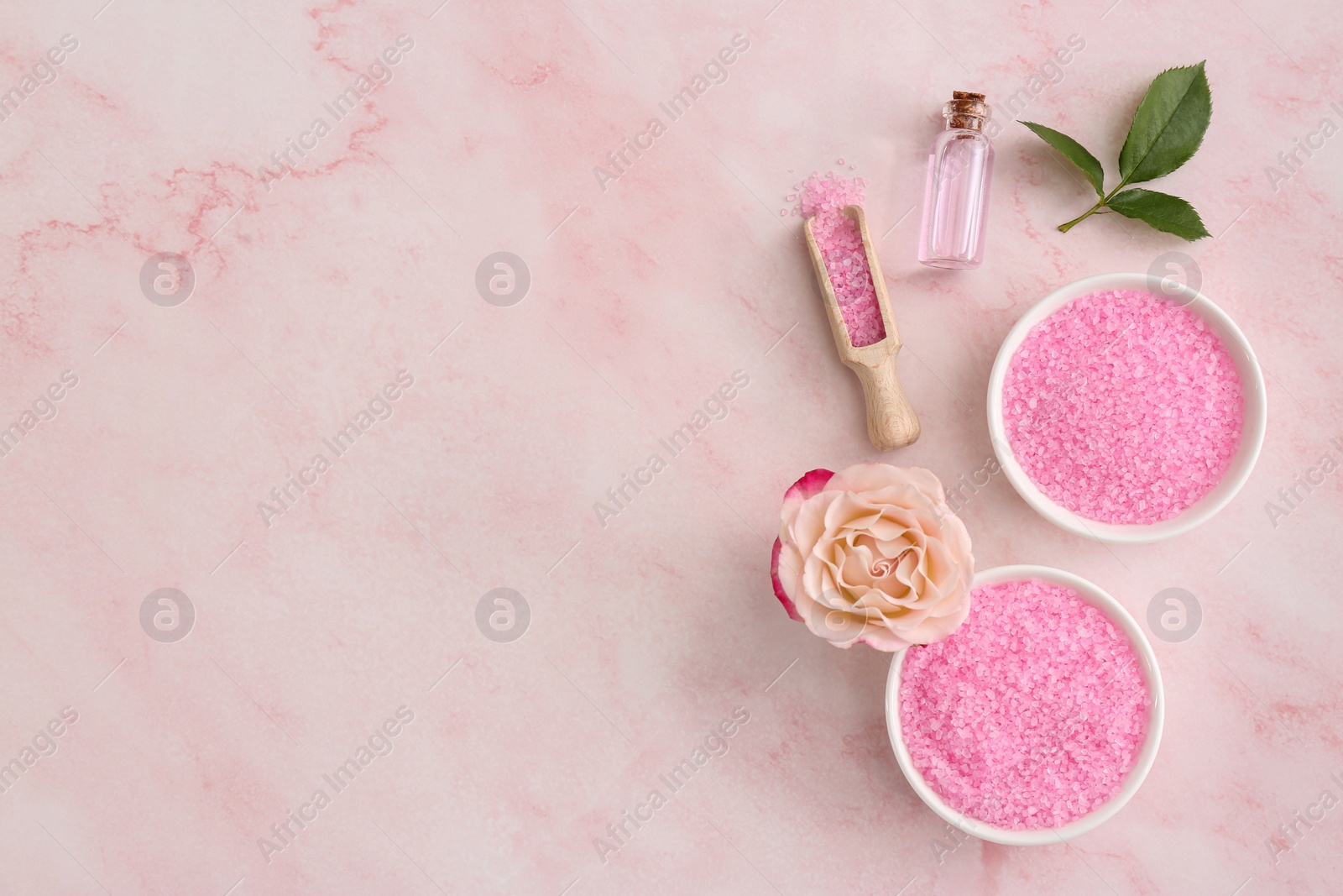 Photo of Bowls and scoop with sea salt, beautiful rose on pink marble table, flat lay. Space for text
