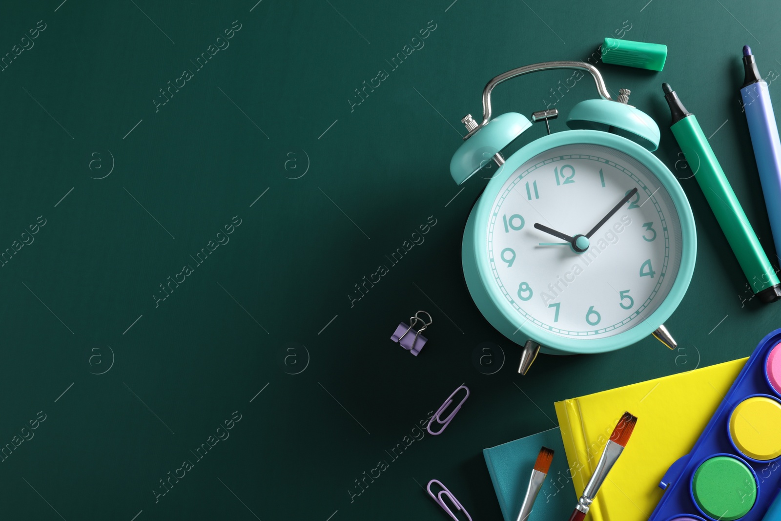 Photo of Flat lay composition with alarm clock and different stationery on green background, space for text. School time