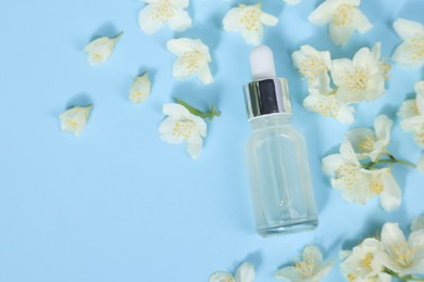 Photo of Essential oil in bottle and beautiful jasmine flowers on light blue background, flat lay. Space for text