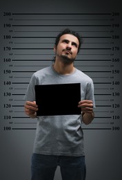 Image of Criminal mugshot. Arrested man with blank card against height chart