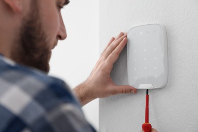 Man installing security alarm system on light wall at home, closeup