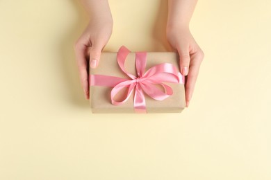 Photo of Woman with gift box on beige background, top view. Space for text