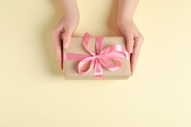 Woman with gift box on beige background, top view. Space for text