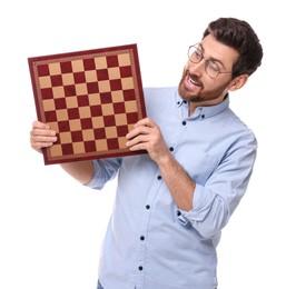 Photo of Emotional man holding chessboard on white background