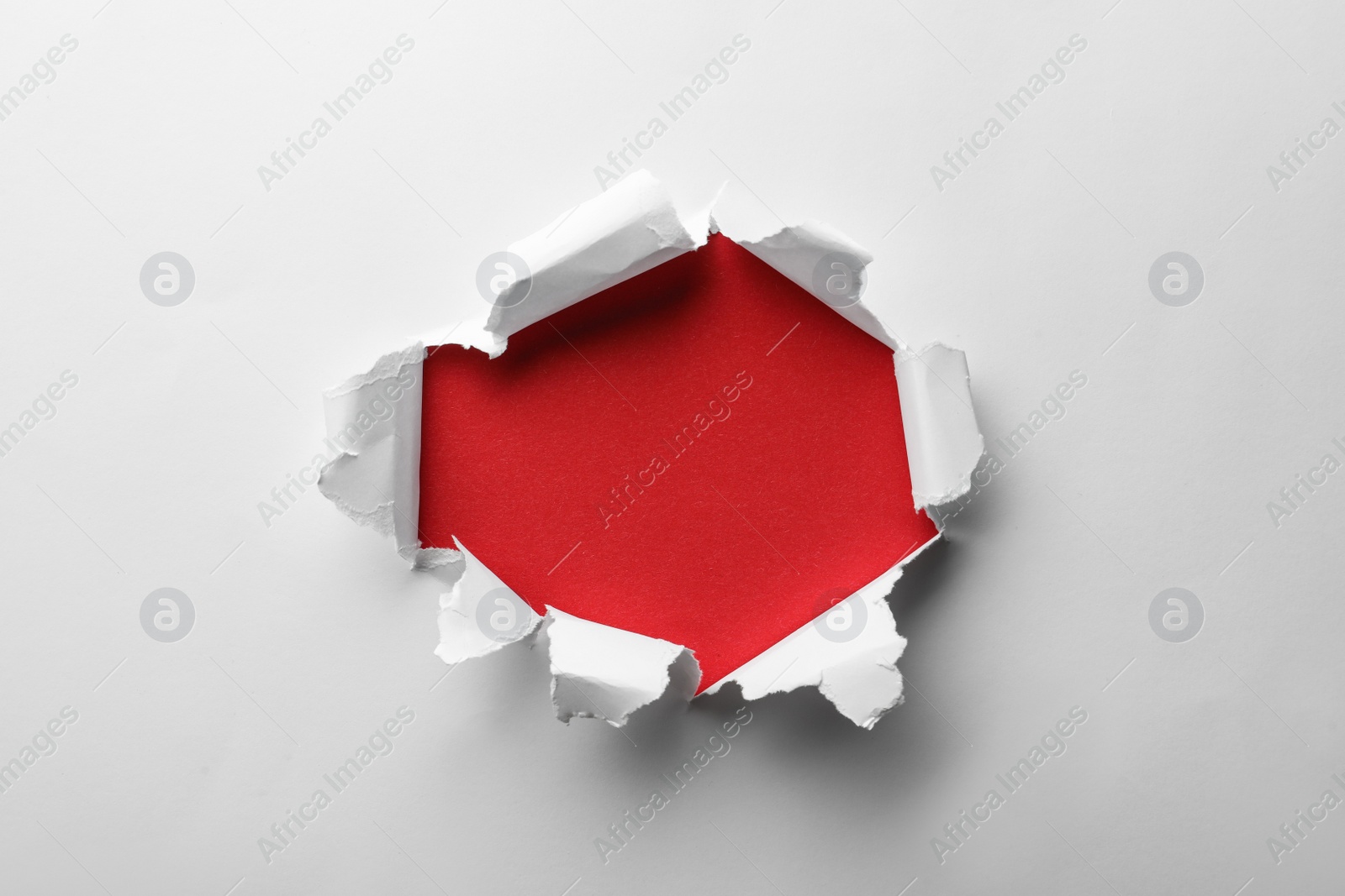 Photo of Hole in white paper on red background