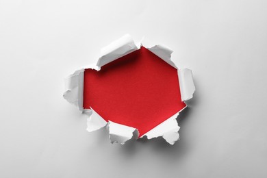 Hole in white paper on red background