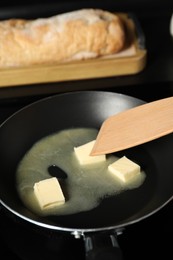 Photo of Stirring melting butter in frying pan at table, closeup