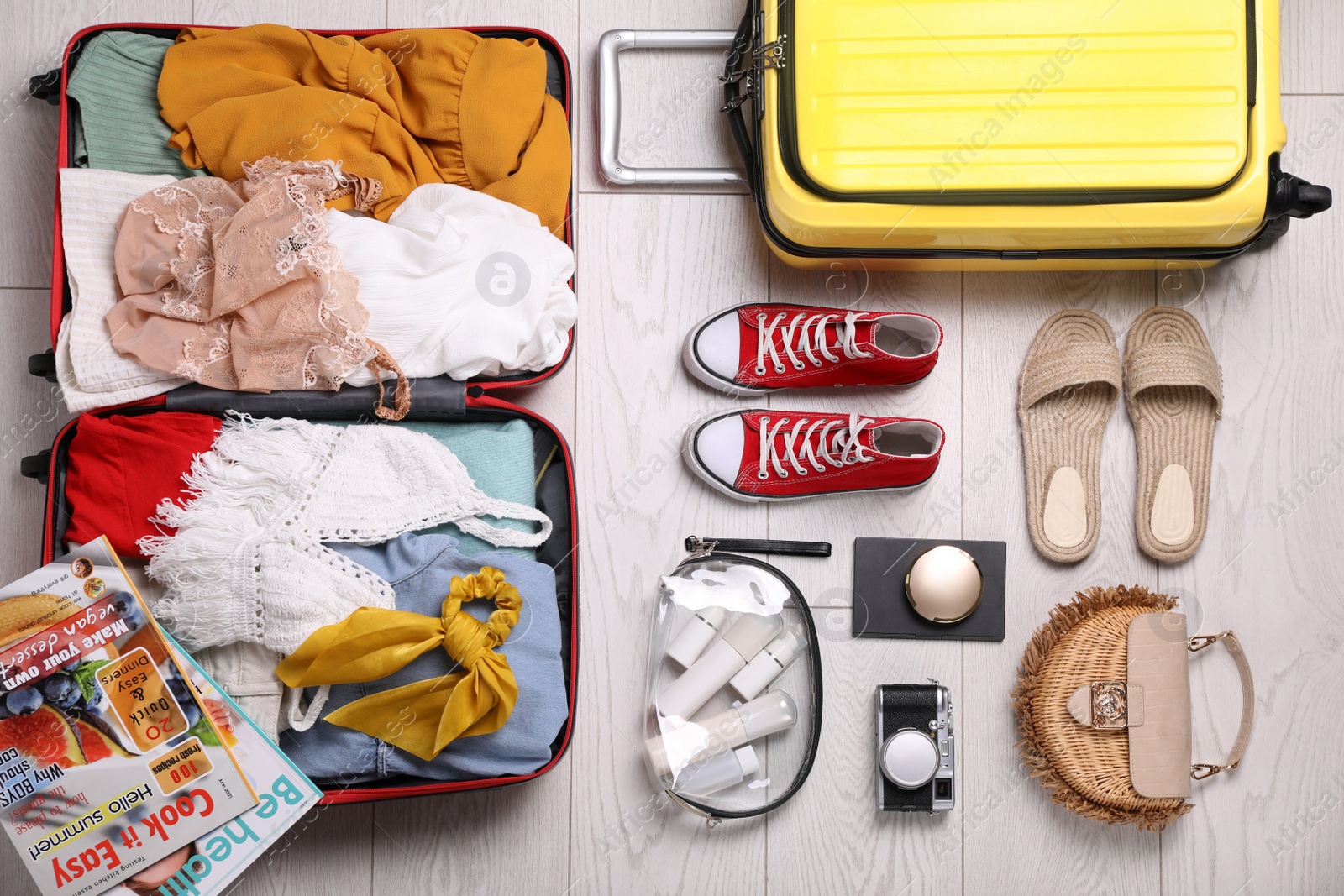 Photo of Suitcases with summer clothes, accessories and shoes on floor, flat lay