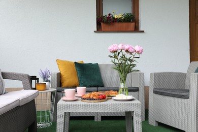 Morning drink, pastry, berries, cheese and vase with flowers on rattan table. Summer breakfast on terrace