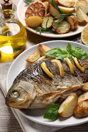 Photo of Tasty homemade roasted crucian carp served on wooden table, closeup. River fish